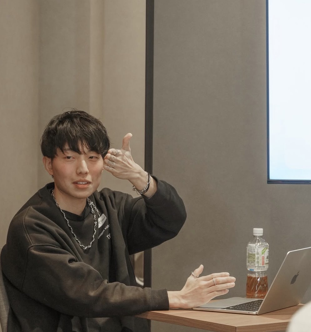 テーブルを囲んでAI活用を説明する渡辺友也